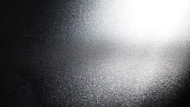 White bokeh and beam on a black background. Blurred glow from above on a dark surface. Night or space theme. Bokeh for the holiday. Abstract background. Glare, ray and light shine from above.