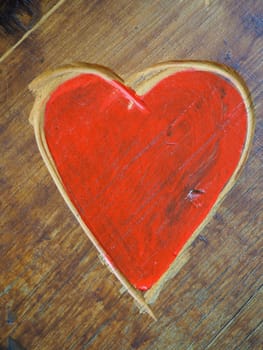 The shape of a heart carved with a knife on a wooden surface and painted in a bright red. A symbol of love and fidelity. Postcard or picture for congratulations or confessions on Valentines Day.