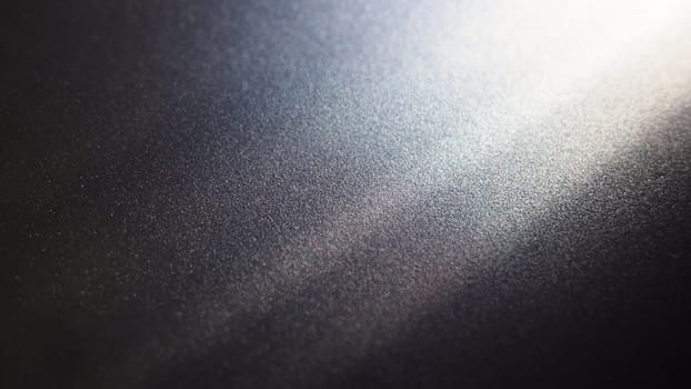 White bokeh and beam on a black background. Blurred glow from above on a dark surface. Night or space theme. Bokeh for the holiday. Abstract background. Glare, ray and light shine from above.
