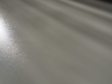 Diagonal rays of light on a gray background. Blurred abstract background light effect, light leaks. Side surface illumination. Small sparks and glow. Shine, glint or glare. Left top right down