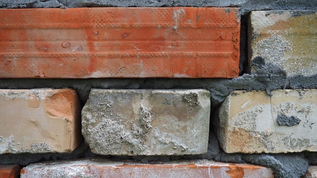 Brick wall. Ceramic masonry or fence. Old, uneven brick, covered in moss and mold in some places. The texture of the stone or mineral. The effect of moisture on brick structures. Village motifs.