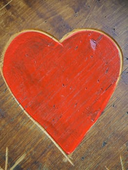 The shape of a heart carved with a knife on a wooden surface and painted in a bright red. A symbol of love and fidelity. Postcard or picture for congratulations or confessions on Valentines Day