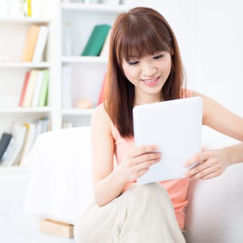 Happy Asian girl downloading new mobile apps, using tablet computer, social networks concept. Young woman indoors living lifestyle at home.
