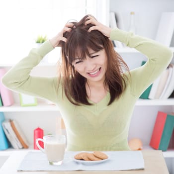 Portrait of Asian girl feeling bored with her breakfast, milk and cookies on dining table. Young people indoors living lifestyle at home.