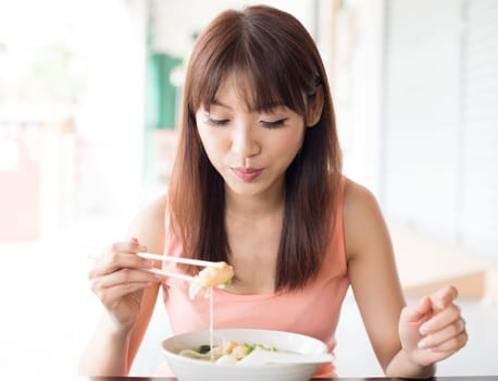 Asian girl eating dumpling noodles at Chinese restaurant. Young woman living lifestyle.