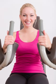 A young pretty woman in a pink shirt doing exercises in a gym