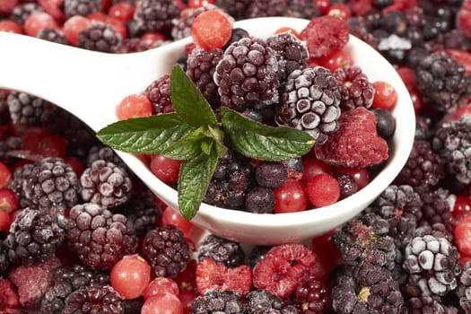 Frozen berries with mint in porcelain bowl
