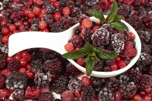 Frozen berries with mint in porcelain bowl