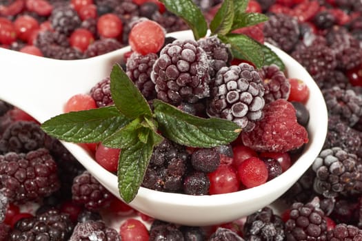 Frozen berries with mint in porcelain bowl