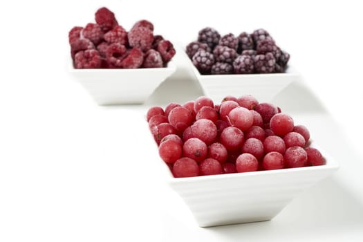 Three bowls of different frozen berries