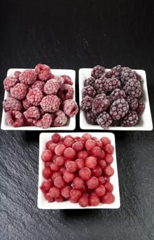 Three varieties of frozen berry fruits in porcelain bowls