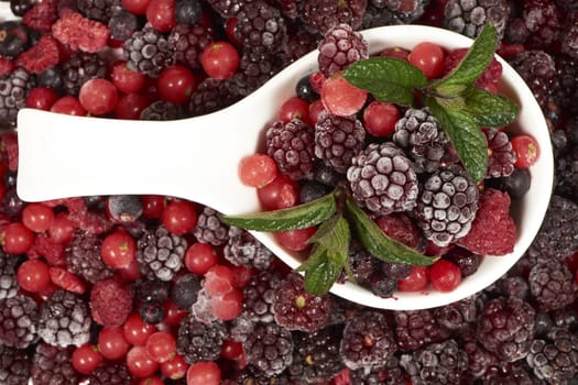 Frozen berries with mint in porcelain bowl