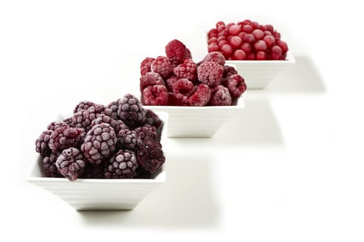 Three bowls of different frozen berries