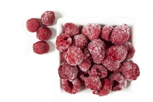 Frozen raspberries in porcelain bowl on white background