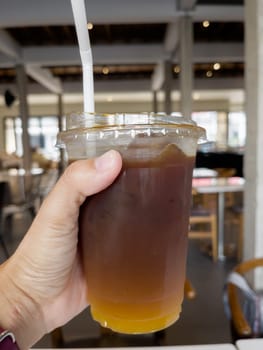 Hand holding glass of iced americano, stock photo