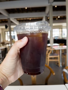 Hand holding glass of iced americano, stock photo