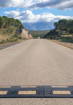 Speed bumps installed a local country road. Snowy mountains background