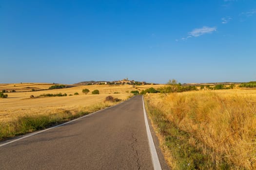 Rural road in the Spanish countryside among agricultural fields, after wheat harvest season. Navarra, Spain
