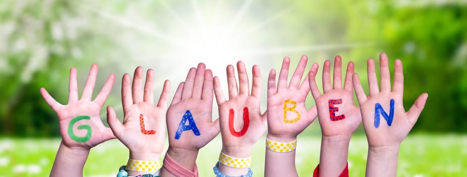 Children Hands Building Colorful German Word Glauben Means Believe. Sunny Green Grass Meadow As Background.