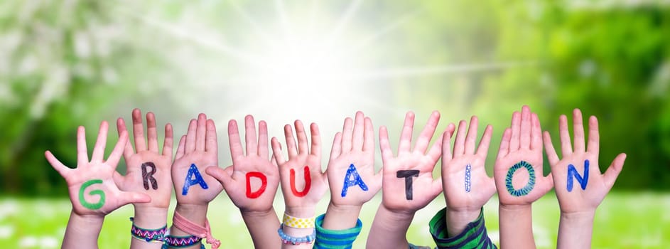 Children Hands Building Colorful English Word Graduation. Sunny Green Grass Meadow As Background.