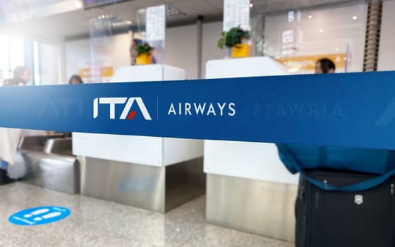 Rome, IT, Jan 2023: Blue barrier tape with the ITA Airways logo inside an airport. ITA Airways is the Italian flag carrier airline . Travel and airport security. Illustrative editorial