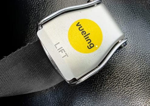 Barcelona, SP Jan 2023: detail of the buckle of the seat belt with the logo of Vueling airlines on an empty seat. Vueling Airlines is a Spanish low-cost airline. Illustrative editorial. Safe travel
