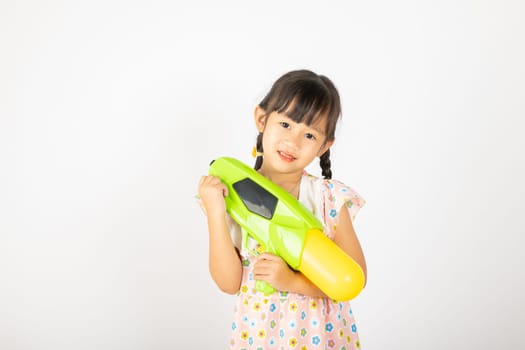 Happy Songkran Day, Asian little girl holding plastic water gun, Thai child funny hold toy water pistol and smile, isolated on white background, Thailand Songkran festival national culture concept