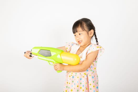 Happy Songkran Day, Asian little girl holding plastic water gun, Thai child funny hold toy water pistol and smile, isolated on white background, Thailand Songkran festival national culture concept