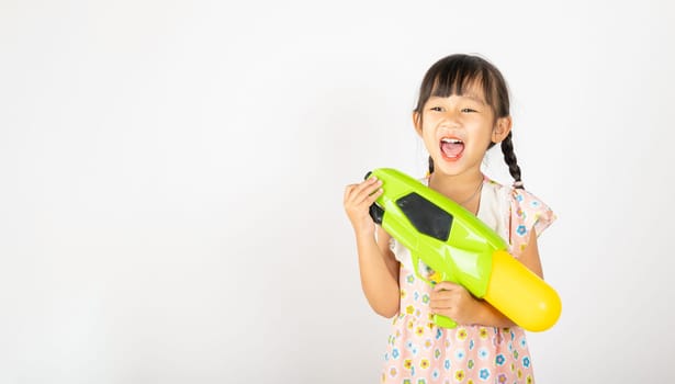 Happy Songkran Day, Asian little girl holding plastic water gun, Thai child funny hold toy water pistol and smile, isolated on white background, Thailand Songkran festival national culture concept