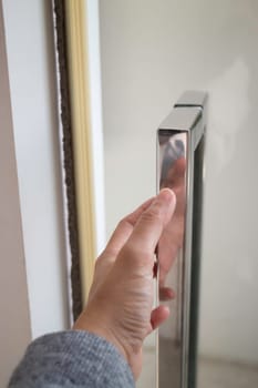 Hand on metal door holder, stock photo