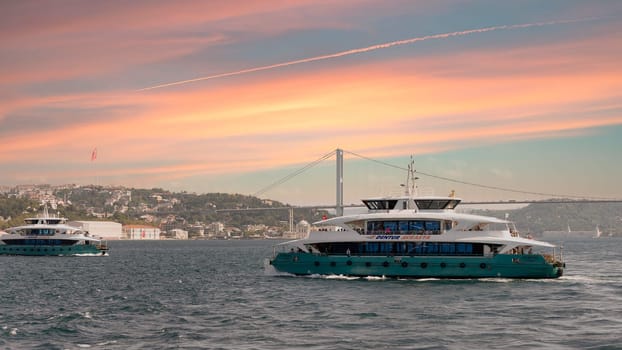 Istanbul, Turkey - August 29, 2022: Modern ferry boat sailing in Bosphorus Strait with Bosphorus bridge in the background, before sunset