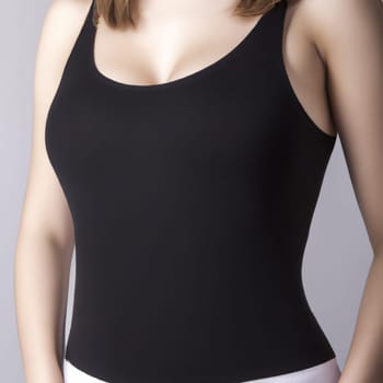 Young beautiful woman in a black tank top with straps, bare shoulders and a beautiful decollete line. Copy space. Female torso, hands. Advertisement for clothing, fitness. Diet and weight loss