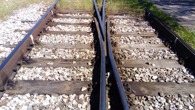 railways. Rails and sleepers on the ground near the station. Long way concept. Interlacing of tracks, railway arrows. Change of direction. Metal heavy rails.