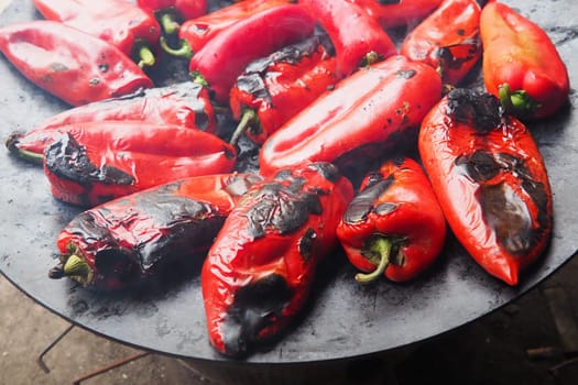 Roasting delicious red peppers for a smoky flavor and quick peeling. Balkan salad recipes. Thermal processing of the pepper crop on a metal circle. Peppers are laid out on a flat baking sheet close-up