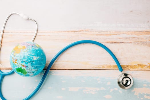 World Health Day. Top view doctor stethoscope wrapped around world globe isolated on wooden background with copy space for text, Save world day, Health care and medical concept