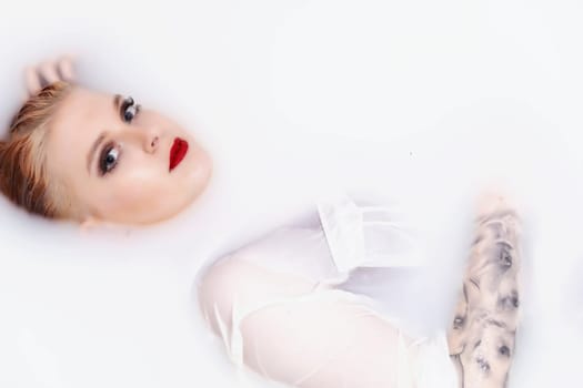 Girl with red lips and  tattoo on her hand is lying  in spa bath with milk. Horizontally.