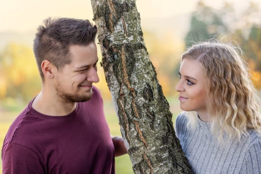 Young loving couple is posing in the autumn park. Horizontally.