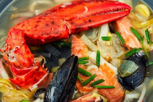 Seafood soup with lobster, mussels, shrimps and fish. Soup in ceramic bowl. Tom yum. Copy space