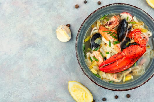 Seafood soup with lobster, mussels, shrimps and fish. Soup in ceramic bowl. Tom yum. Copy space