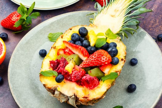Fruit salad of strawberries, kiwi, berries and orange served in half a pineapple. Healthy eating