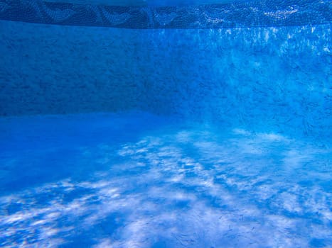 Dreamy clean blue pool interior shot underwater with dolphin boeder and ripples of light and shadow.