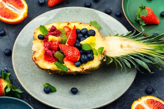 Fruit salad of strawberries, kiwi, berries and orange in pineapple. Concept of low calorie delicious desserts