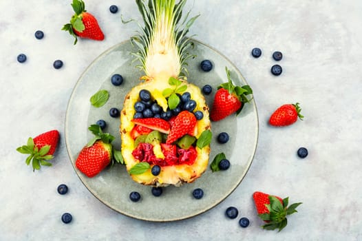 Fruit salad of strawberries, kiwi, berries and orange in pineapple. Concept of low calorie delicious desserts