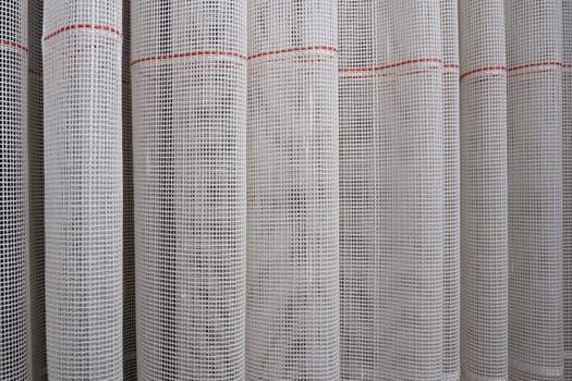 White coarse cotton or linen curtains made of weaves of thin threads. Simple compact economical apartment interior. Window decoration in the room. Red stripe