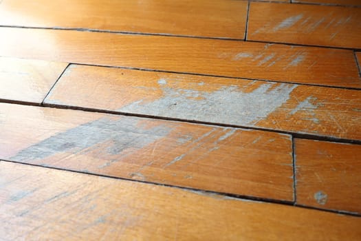 Old, scratched parquet flooring needs maintenance. The parquet is damaged by scratches from prolonged use.