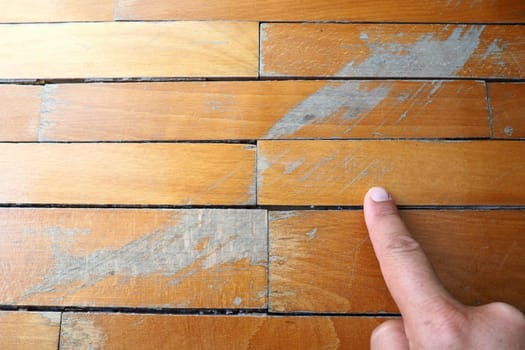 Old, scratched parquet flooring needs maintenance. the parquet is damaged by scratches from prolonged use. Master's hands show damage to the floor.