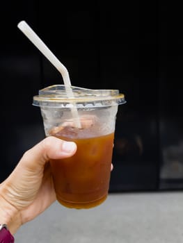 Hand holding glass of iced americano, stock photo