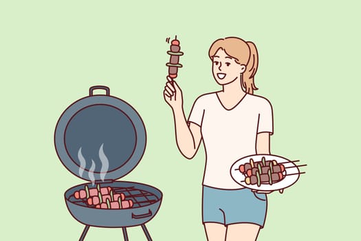 Woman barbecues on outdoor grill in backyard of home preparing for picnic party. Girl fries barbecues meat and BBQ vegetables on hot coals, wanting to get delicious snack with smell of smoke