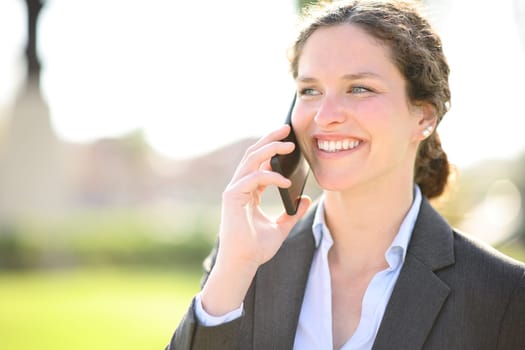 Happy businesswoman using cell phone smiling in a park