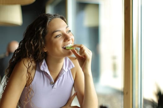Woman eating kiwi in a restaurant looking through a window